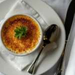 Finished crab brulee with golden caramelized crust, garnished with parsley and served on a white plate