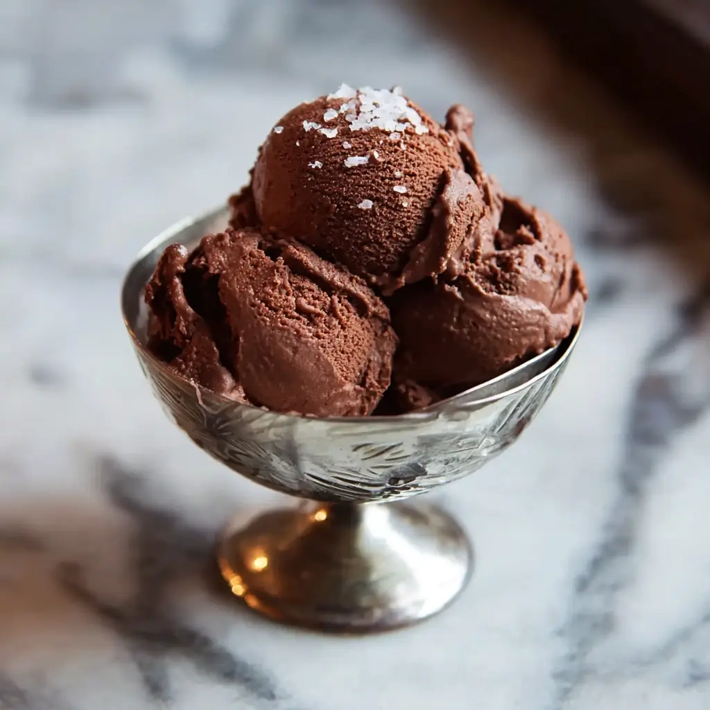 Scoops of David Lebovitz’s chocolate sorbet in a bowl with chocolate shavings and a silver scoop.