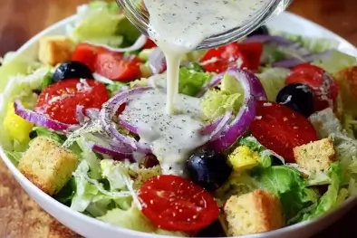 Copycat Olive Garden Salad topped with dressing, Parmesan, and croutons in a white serving bowl.