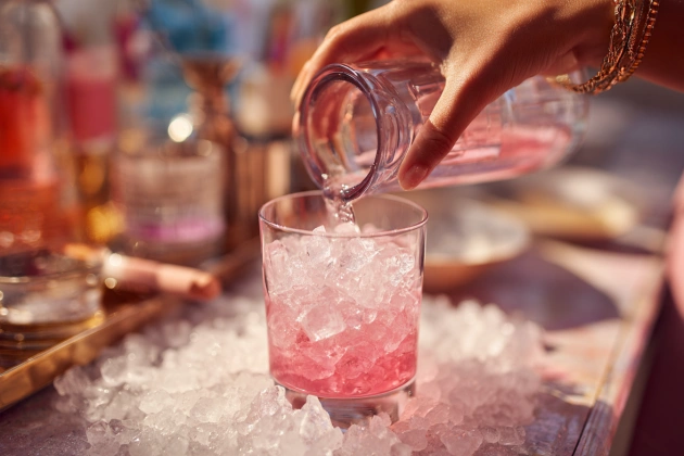 ocktail shaker filled with pink liquid being shaken over ice.