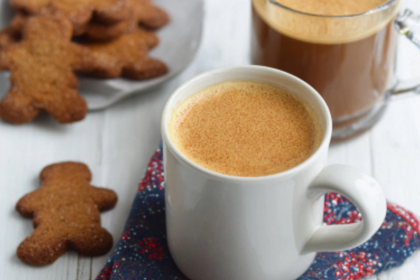 A steaming mug of Gingerbread Coffee, garnished with whipped cream, cinnamon, and a cinnamon stick, perfect for cozy winter days.